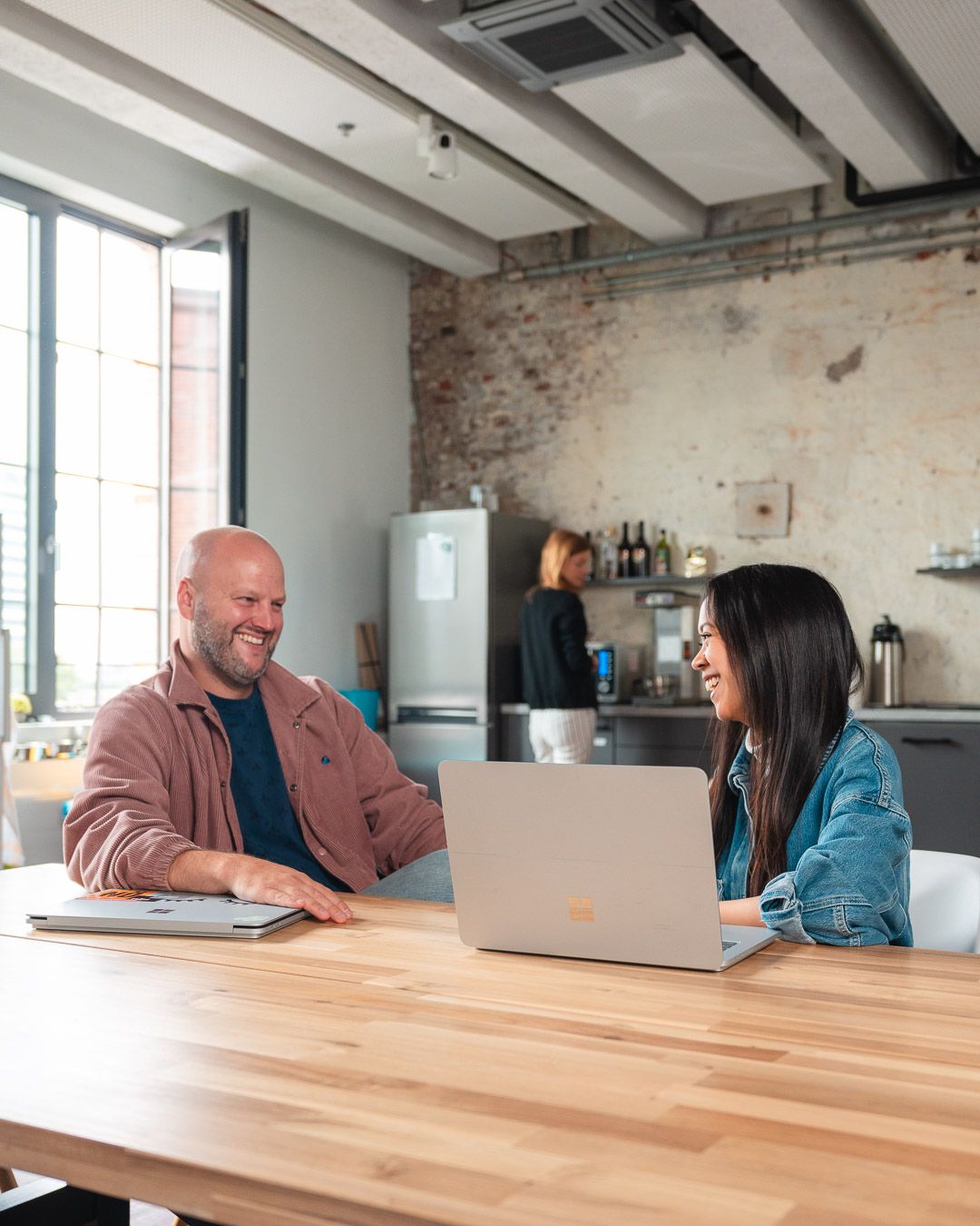 Two colleagues sitting next to each other smiling 